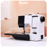 Modern electric sewing machine with detailed stitch settings on display, ideal for home workshops, shown in a cozy room setting.