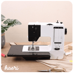 Modern electric sewing machine on a sewing table, surrounded by sewing supplies.