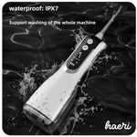 Black L12 oral irrigator with waterproof IPX7 rating, cordless design, floating in water, showing control buttons.